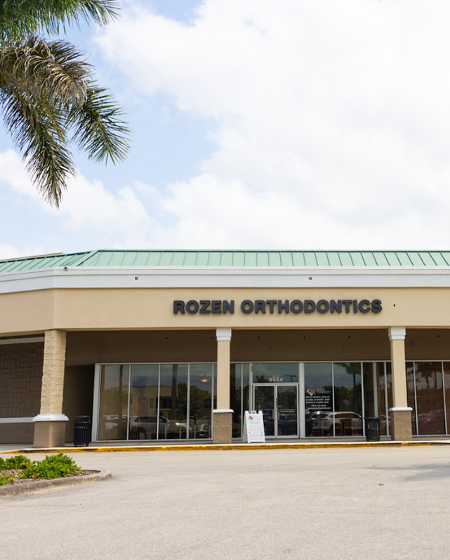 Rozen Orthodontics storefront exterior with entrance doors and signage in commercial plaza setting.