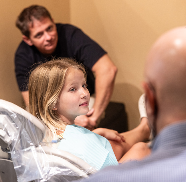 Young patient receiving orthodontic examination from dentist in clinical office setting.
