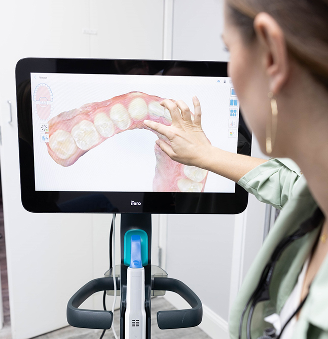 Woman examines digital dental model on monitor in orthodontic clinic treatment consultation.